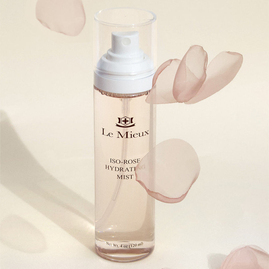 Iso-Rose Hydrating Mist with light pink rose petals falling around it in front of a light yellow background