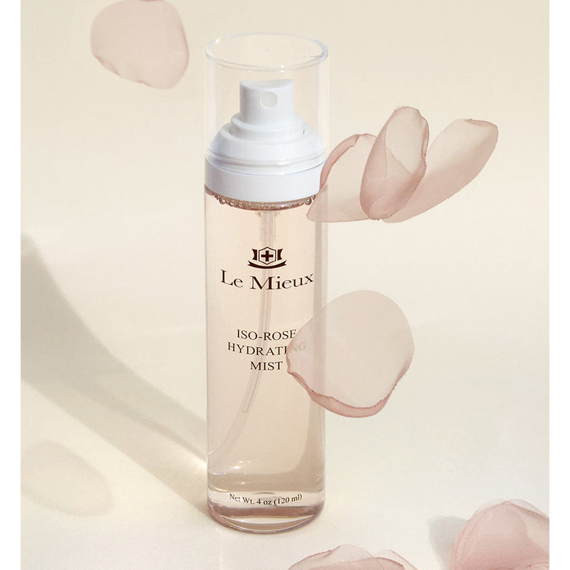 Iso-Rose Hydrating Mist with light pink rose petals falling around it in front of a light yellow background